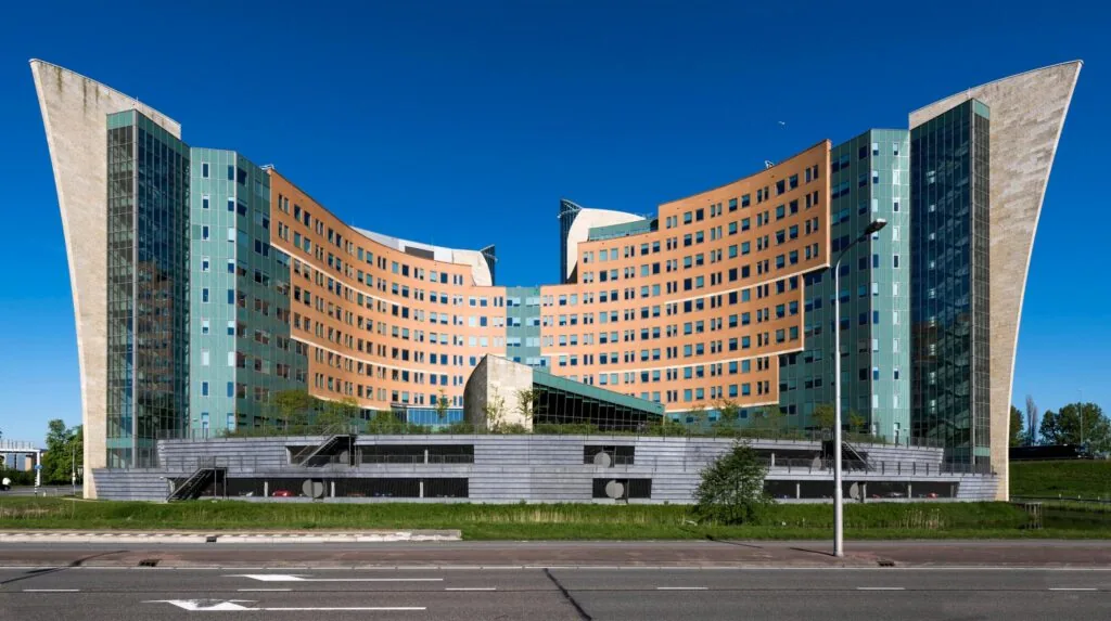 Kantoorgebouw aan de Laan van Langerhuize met kenmerkende gebogen gevels en glazen elementen, gefotografeerd op een zonnige dag.